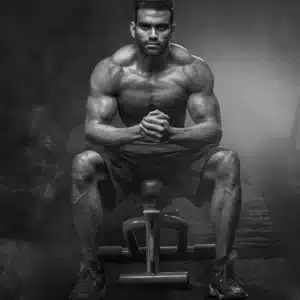 Muscular man sitting on bench and flexing muscles