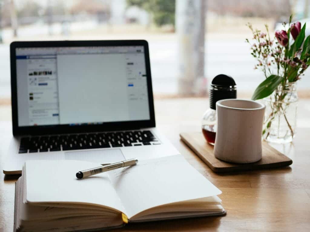 Work desk with laptop, coffee, and a notebook