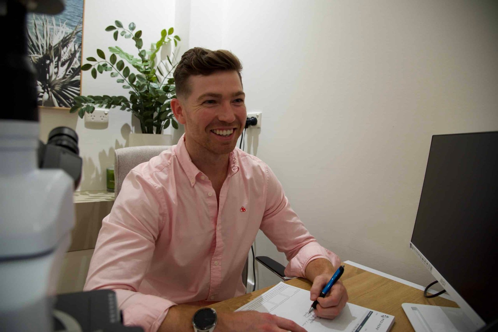 Naturopath smiling while doing paperwork at his desk