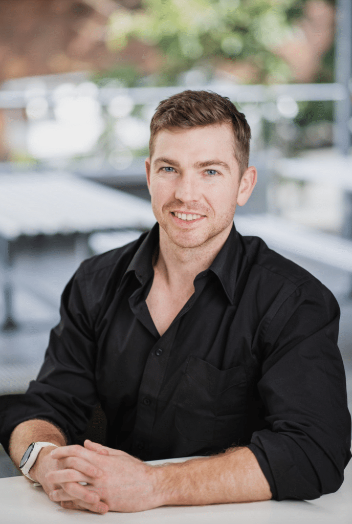 Functional medicine practitioner sitting at white table and smiling.
