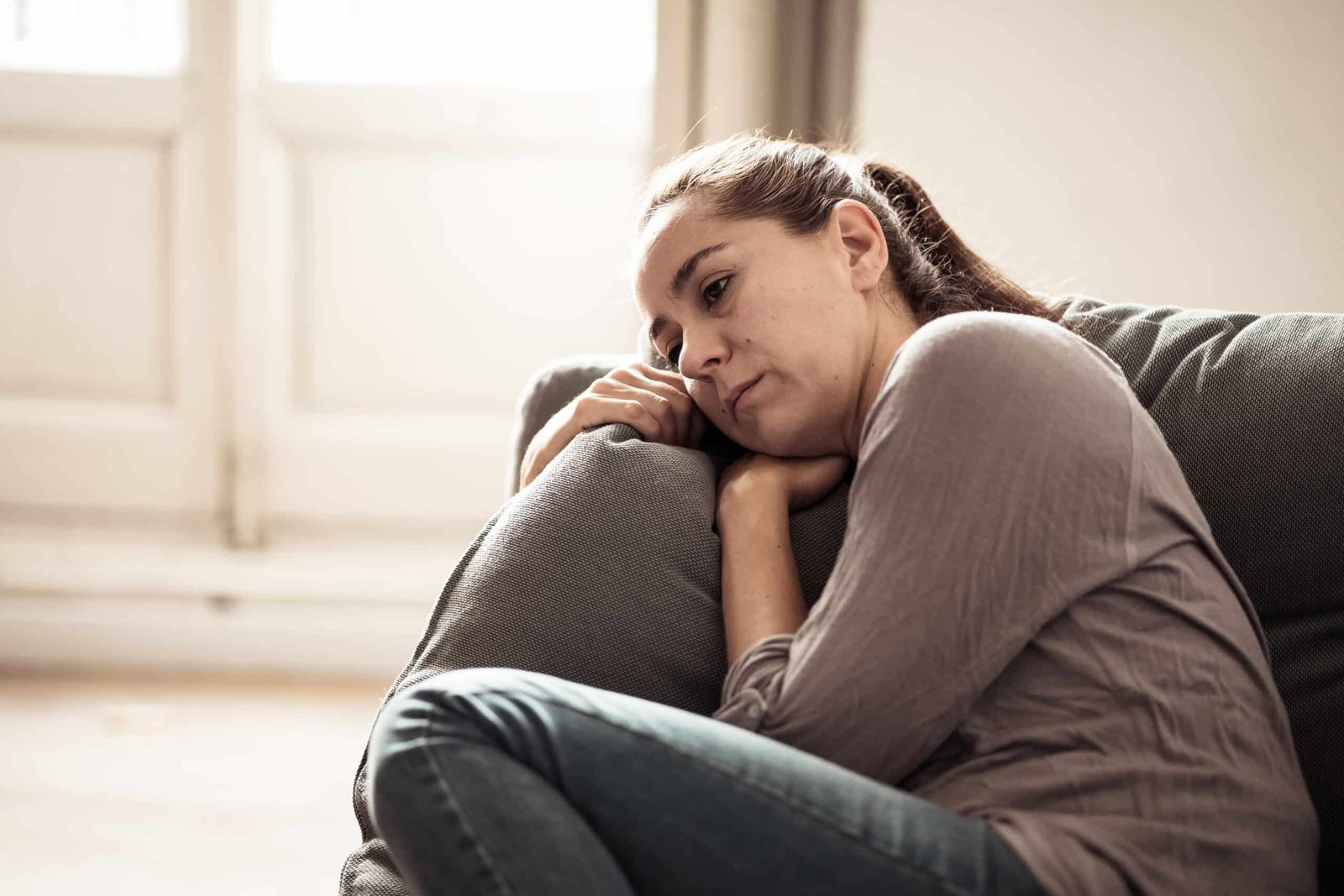 Woman sitting on her coach sad about IBS problems